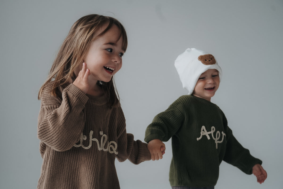 Kinder mit personalisierten Strickpullovern mit Namen in Taupe und Waldgrün