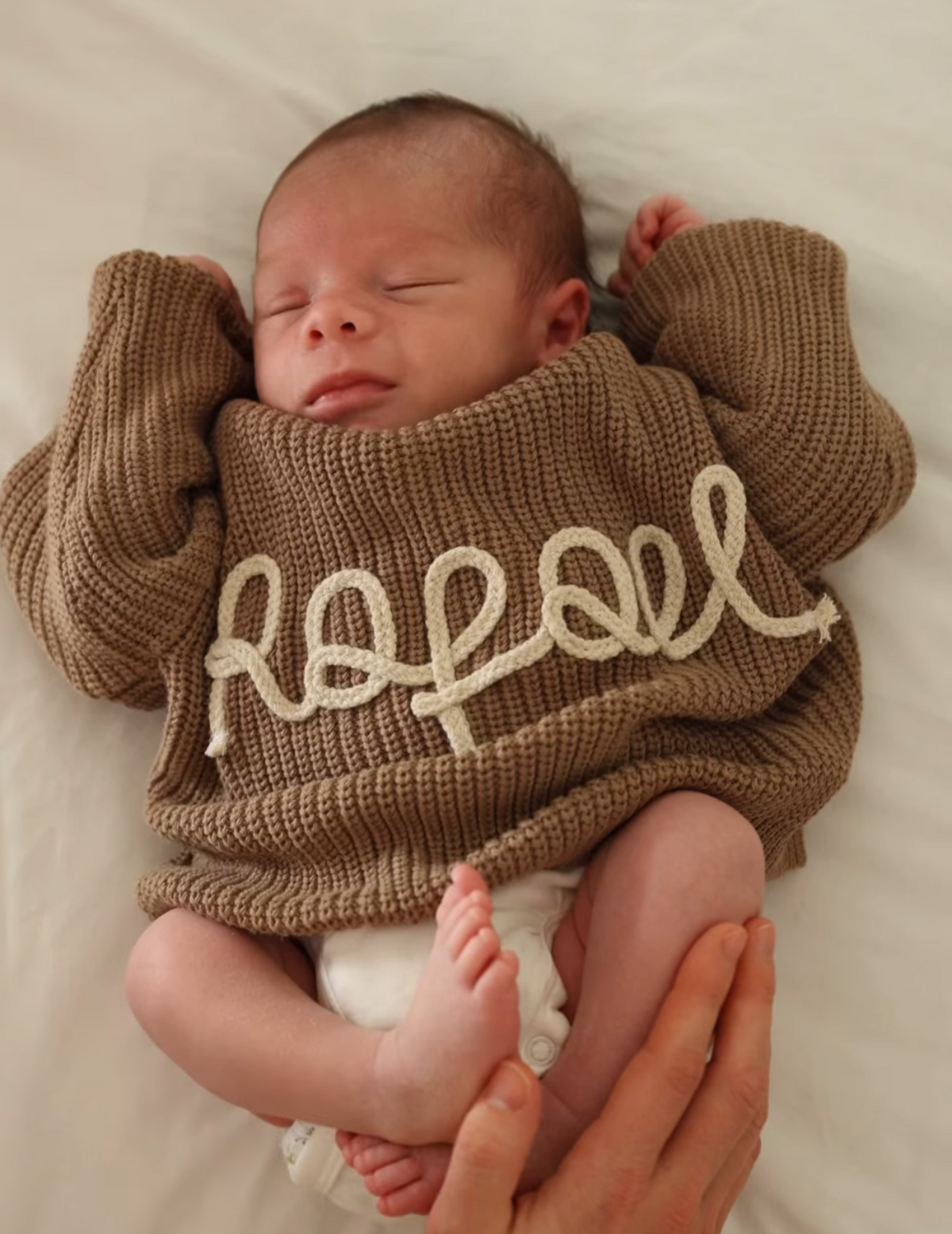 Baby mit personalisiertem Strickpullover mit Namen in Taupe