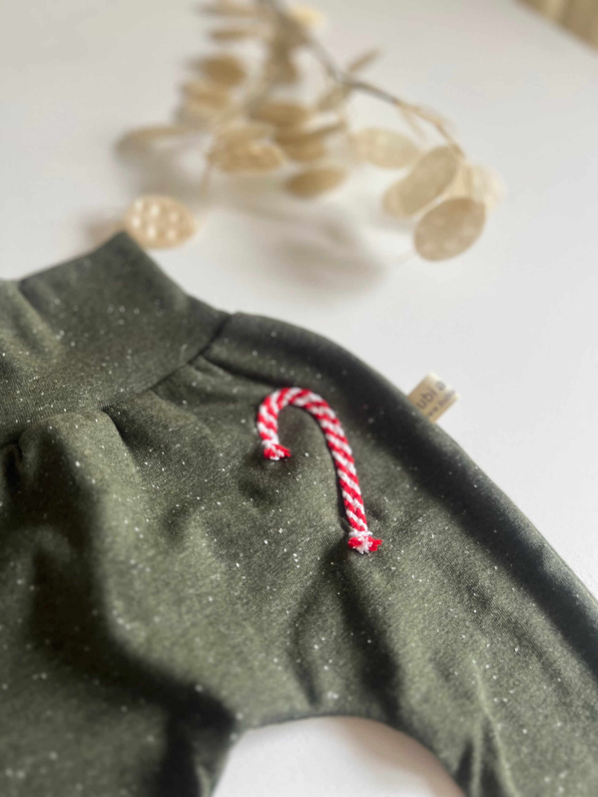 Detail der grünen Weihnachtshose mit rot-weißer Zuckerstange und Konfetti-Sprenkeln